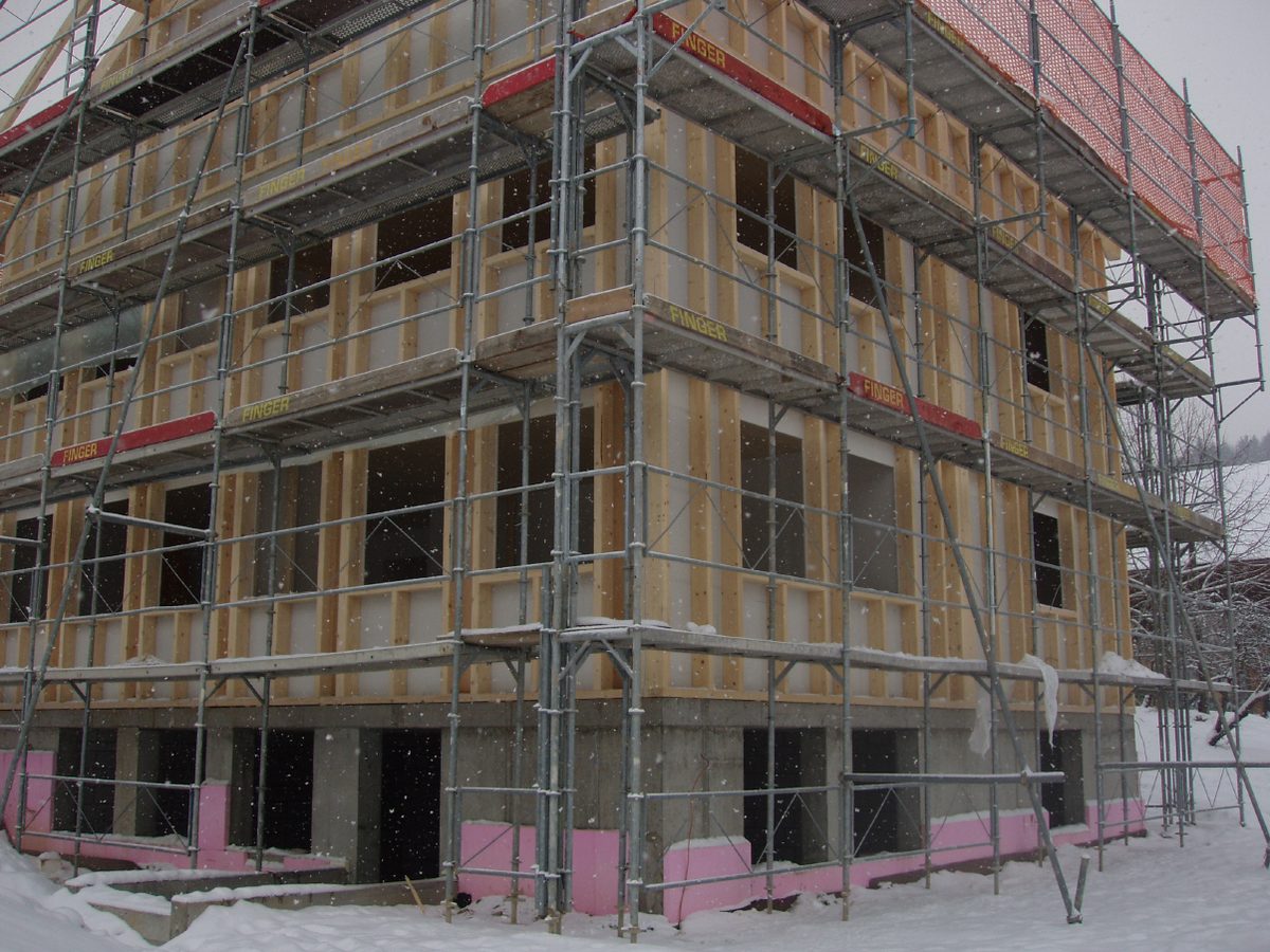 Mehrfamilienhaus in Holzelementbauweise mit Gerüst im Winter