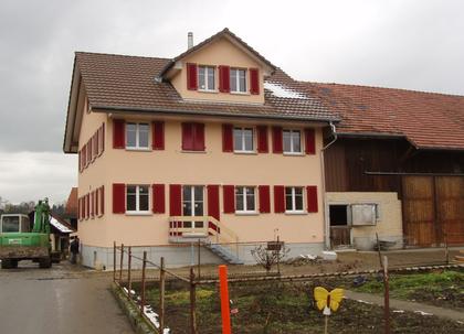 Neues Wohnhaus mit roten Fensterläden nach dem Wiederaufbau